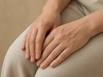 Hands resting on linen-covered knees, with the wrists and fingers in view